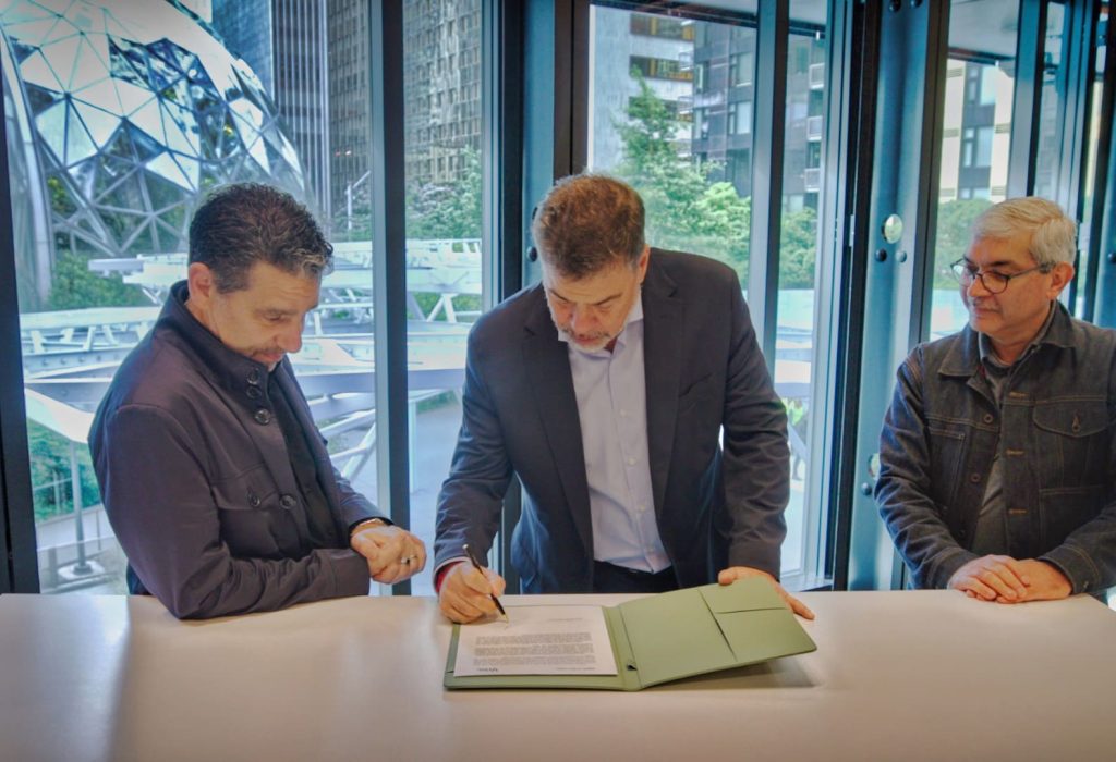 Darío Werthein firma el acuerdo con Rajeev Badyal y Panos Panay